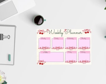 May include: A weekly planner with pink boxes for each day, adorned with red bows and cherries. The words "Weekly Planner" are written in cursive. A notebook, coffee cup, and teapot are also visible.
