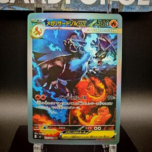 May include: A holographic trading card featuring a Mega Charizard X EX. The card has a fiery and blue color scheme with Japanese text. The card shows a dragon-like creature with flames and blue energy.