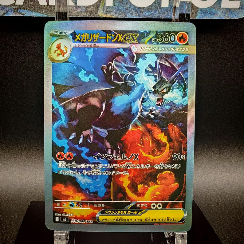 May include: A holographic trading card featuring a Mega Charizard X EX. The card has a fiery and blue color scheme with Japanese text. The card shows a dragon-like creature with flames and blue energy.