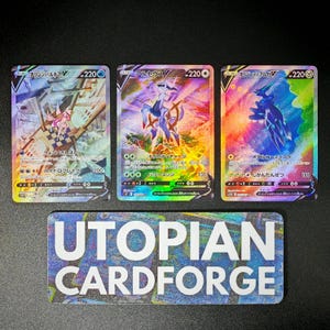 May include: Three holographic trading cards featuring colorful illustrations of fantasy creatures and Japanese text. The cards are labeled with numbers and Japanese characters. Below the cards is a rectangular sticker with the text "UTOPIAN CARDFORGE".