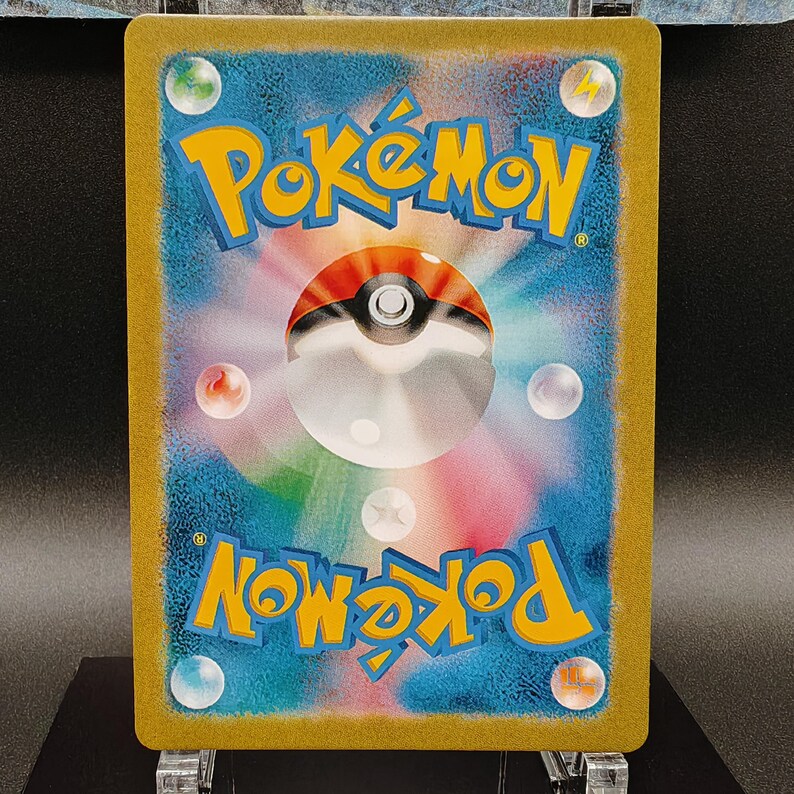 May include: A Pok&eacute;mon trading card featuring a vibrant design. The card's background is a gradient of blue and purple, with a central Pok&eacute; Ball design. The word "Pok&eacute;mon" is in yellow, and the card has a gold border.