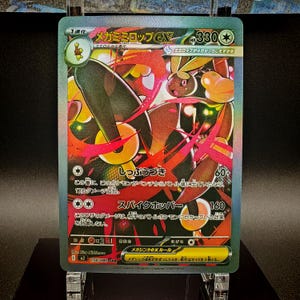 May include: A holographic Pok&eacute;mon trading card featuring a Mega Lopunny EX. The card has a green border and displays a colorful illustration of the character. Japanese text is visible, along with attack details and HP.