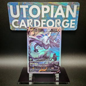 May include: A Pokemon trading card featuring Lugia V, a blue and white legendary Pokemon with a wingspan, in a holographic style. The card is from the Sword & Shield - Vivid Voltage set and has a number of 220.