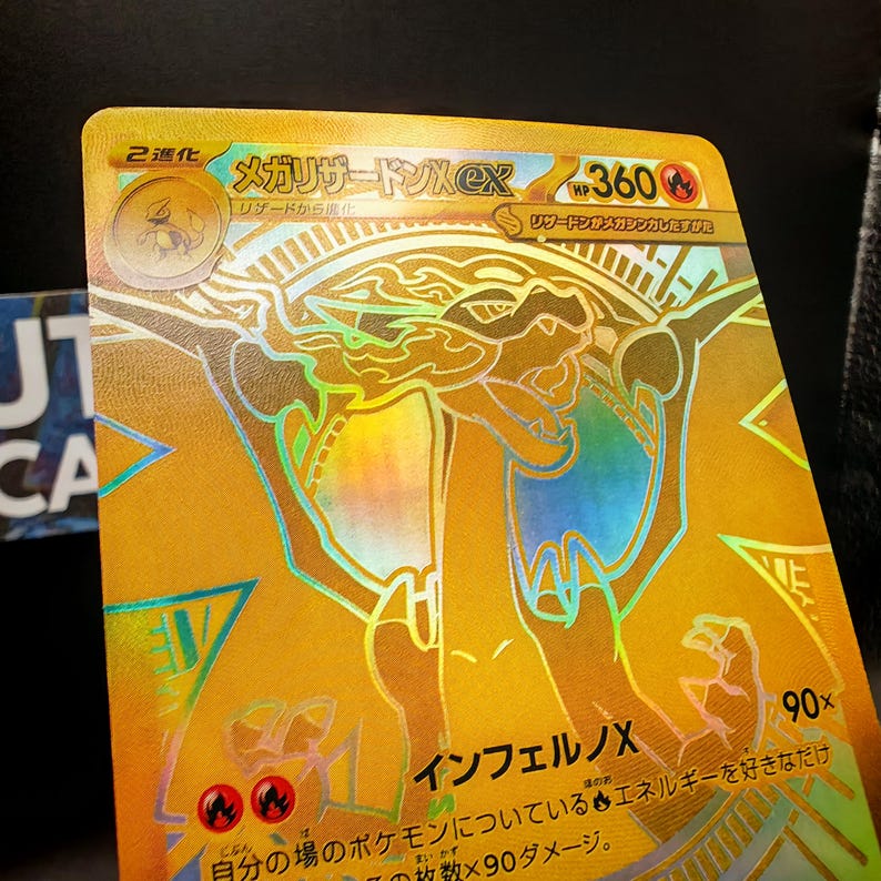 May include: A gold-colored trading card featuring a holographic illustration of a dragon-like creature. Japanese text is visible, along with the number "360" and the text "90x". The card has a shiny, reflective surface.