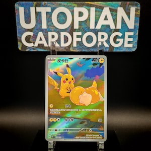 May include: A holographic trading card featuring Pikachu, a yellow creature with red cheeks, in a colorful landscape. The card has Japanese text and a power rating of 60. The card is displayed in a clear holder with the text "UTOPIAN CARDFORGE" above.