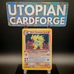 Könnte beinhalten: Eine gelbe und schwarze Dark Tyranitar Pokémon-Karte aus dem Pokémon Sammelkartenspiel. Die Karte zeigt eine Illustration von Dark Tyranitar vor einem roten Hintergrund. Der Kartentext lautet "Dark Tyranitar 90 KP" und beinhaltet die Attacken "Mountain Smasher" und "Fling Away".