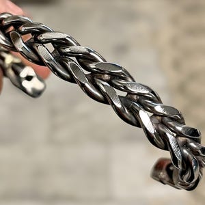 May include: A silver braided cuff bracelet with a textured finish.