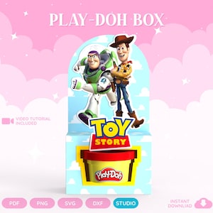 May include: A light blue box with a cloud pattern featuring Buzz Lightyear and Woody from Toy Story at the top. The box has a central cutout displaying a yellow Play-Doh container with a red lid. The text PLAY-DOH BOX is at the top.
