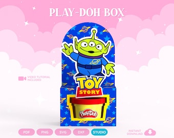 May include: A blue cardboard display box featuring a green three-eyed alien character in a blue space suit, the Toy Story logo, and a yellow cutout window holding a yellow Play-Doh container with a red lid. The text reads PLAY-DOH BOX.
