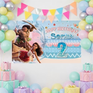 May include: A rectangular birthday backdrop featuring Moana and Maui characters, with the text "HAPPY BIRTHDAY SOPHIA" and the number "2" displayed prominently. The scene is framed by a colorful balloon arch in pastel shades and gift boxes.