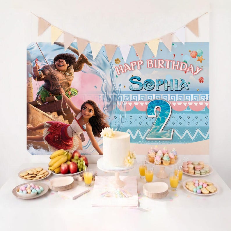 May include: A birthday party backdrop featuring Moana and Maui characters, the text "HAPP BIRTHDAY SOPHIA" and a large number "2". The table includes a white cake, plates of cookies, cupcakes, fruit, and glasses of orange juice with a banner above.