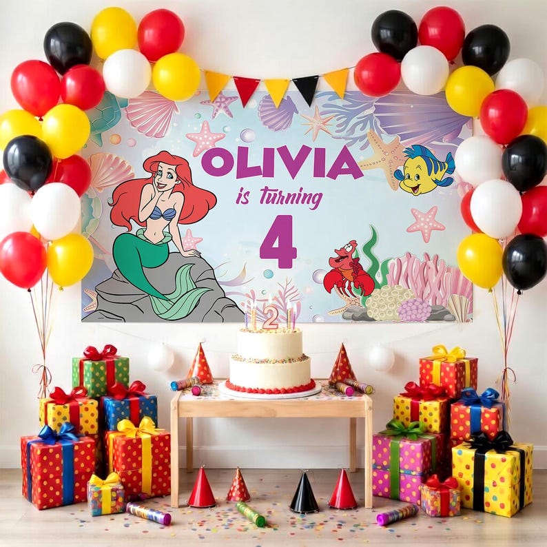 May include: A birthday party setup featuring a backdrop with the text OLIVIA is turning 4, an illustration of a mermaid, a crab, and a fish. A white cake with a number 2 candle sits on a table surrounded by colorful gift boxes and balloons.