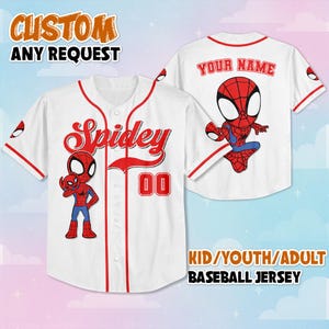 以下が含まれることがあります： 赤色のトリムと赤色のスクリプトで「Spidey」という文字が入った白い野球ジャージ。漫画のスパイダーマンのグラフィックと数字の「00」が特徴です。ジャージの背面にはスパイダーマンのグラフィックと「YOUR NAME」という文字があります。上部のテキストは「CUSTOM ANY REQUEST」と書かれています。