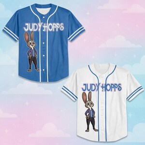 May include: Two short-sleeve button-down baseball jerseys, one blue and one white, each featuring a graphic of the character Judy Hopps and the text "JUDY HOPPS" printed on the front. Both jerseys have white piping along the placket and sleeves.