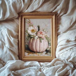 May include: A framed vintage print depicting a pink pumpkin adorned with white and pink flowers. The artwork is in a gold frame, set against a cream backdrop. The text "ARTEAWALLPRINTS Vintage Printed Art" is at the bottom of the image.