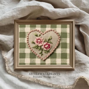 Può includere: Un'opera d'arte incorniciata con un ricamo a forma di cuore con fiori rosa e foglie verdi. Il cuore è bordato da perline rosa su uno sfondo a scacchi verdi e bianchi. La cornice è marrone chiaro, con il testo "ARTEAWALLPRINTS Printable Vintage Art".