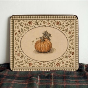 May include: A rectangular serving tray featuring a central illustration of an orange pumpkin within an oval frame. The border displays a brown and cream checkered pattern and a decorative floral vine motif in shades of green, brown, and red.
