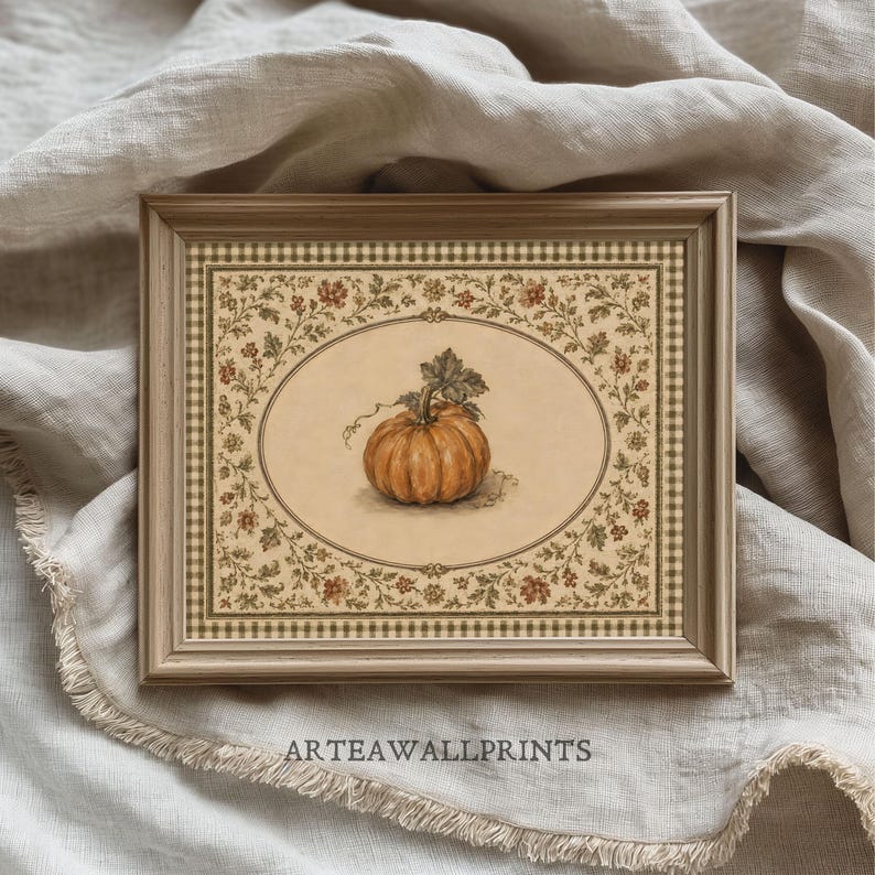May include: A framed rectangular print featuring a central orange pumpkin illustration within an oval border. The surrounding frame displays a beige and brown checkered pattern with a decorative floral vine motif. The text ARTEAWALLPRINTS is visible.