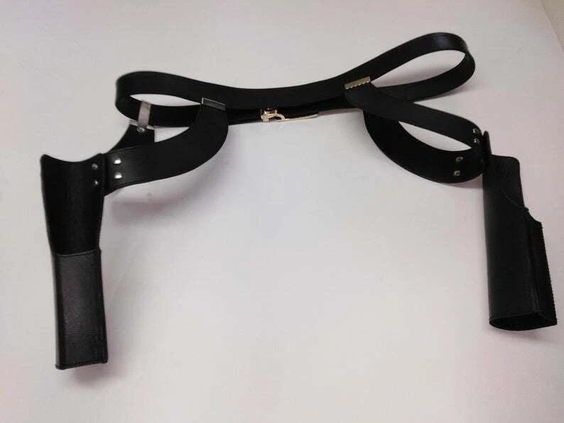 May include: Black leather shoulder holster with two attached pouches. The holster has a belt that wraps around the torso and connects to the shoulder straps. The pouches are designed to hold items, and the holster is secured with metal hardware.