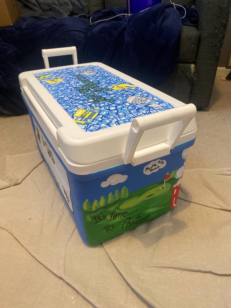 May include: A white and blue cooler featuring a golf course design. The lid is white with a blue and yellow pattern. The side displays the text "It's Time To Partee". The cooler has white handles for easy carrying.