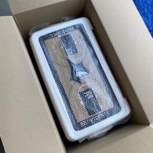 May include: A white and black basketball backboard with the text "PROVIDENCE" and "BIG EAST" inside a cardboard box. The backboard is wrapped in bubble wrap.