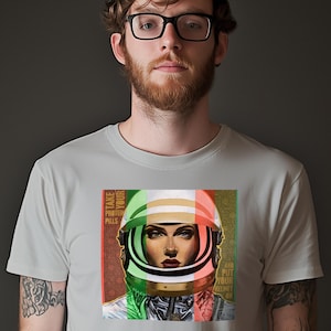 May include: A gray t-shirt with a graphic of a woman wearing a space helmet. The helmet is decorated with green, white, and red stripes. The text on the graphic reads "Take Your Printed Pills".