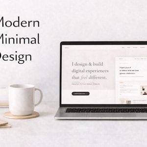 May include: A laptop displaying a website design with the text "I design & build digital experiences that feel different." A white mug, notepad, and a small succulent are on the desk. The words "Modern Minimal Design" are at the top.