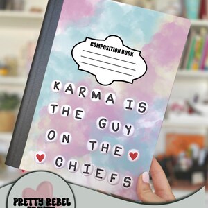 May include: Composition notebook cover with a watercolour design in shades of pink, blue, and white. The cover features the text "KARMA IS THE GUY ON THE CHIEFS" with red heart accents. The notebook has a black spine and a label that says "COMPOSITION BOOK".