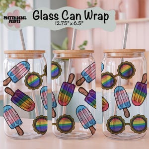 Peut inclure: Trois gobelets en verre transparents avec couvercles en bambou et pailles en acier inoxydable. Chaque verre présente des motifs colorés de sucettes glacées et de lunettes de soleil arc-en-ciel. Le texte "Glass Can Wrap" et les dimensions (32.39 cm x 16.51 cm) sont visibles.