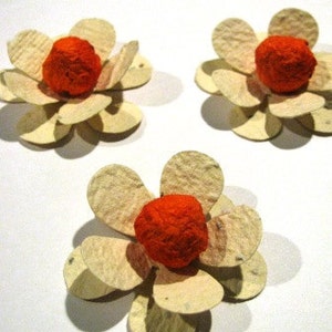 K&ouml;nnte beinhalten: Drei Papierblumen mit orangenen Zentren und wei&szlig;en Bl&uuml;tenbl&auml;ttern. Die Blumen sind aus Recyclingpapier hergestellt und eine gro&szlig;artige M&ouml;glichkeit, Ihrem Zuhause einen Hauch von Farbe zu verleihen.