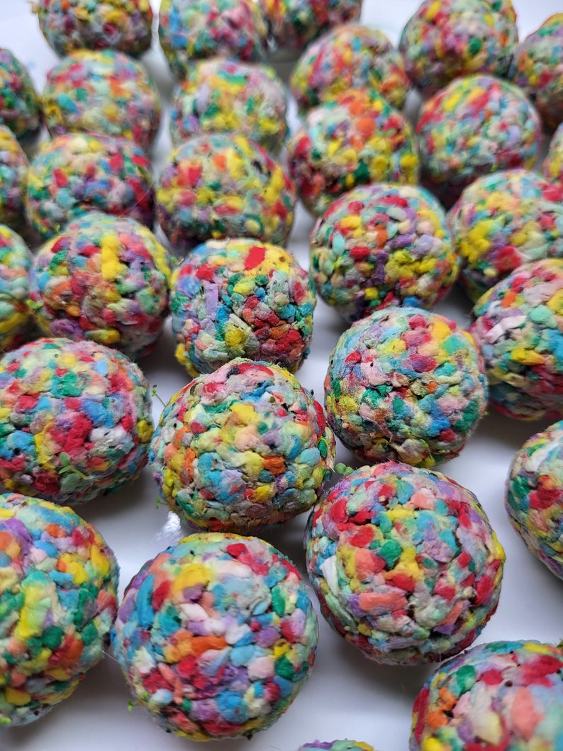 May include: A collection of colorful, handmade, confetti-filled balls. Each ball is made of a variety of colors, including red, blue, green, yellow, and purple. The balls are all about the same size and are arranged in a random pattern.