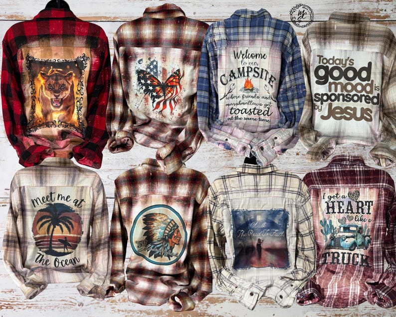 May include: Collection of plaid button-down shirts with various graphic designs. Designs include a tiger, a butterfly with an American flag theme, a campsite scene, and the text "Today's good mood is sponsored by Jesus". Other shirts feature a Native American, a truck, and ocean themes.