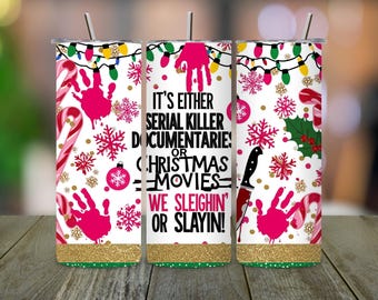 May include: A white tumbler with a gold glitter base, featuring pink handprints, snowflakes, candy canes, and the text "IT'S EITHER SERIAL KILLER DOCUMENTARIES OR CHRISTMAS MOVIES WE SLEIGHIN' OR SLAYIN!".