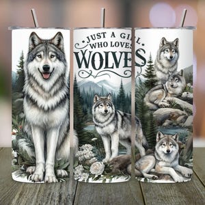 May include: Three stainless steel tumblers with a white background and wolf illustrations. The tumbler on the left features a gray wolf with black markings. The tumbler in the middle has the text "Just a girl who loves wolves". The tumbler on the right features a gray wolf with black markings and a smaller wolf sitting on its back.