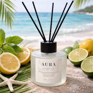 May include: Aura Sea Salt & Ocean reed diffuser with black reeds, lemons, limes, and a starfish. The diffuser is in a clear glass bottle with a black cap. The label reads "Aura District Co. Sea Salt & Ocean Reed Diffuser 100ml / 3.4 fl. oz."