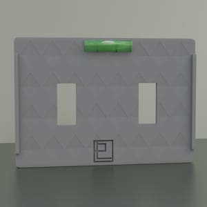 Puede incluir: Una placa de pared gris con un patrón de chevron y dos recortes rectangulares. Un nivel de burbuja verde está unido a la parte superior de la placa. La placa tiene un pequeño logotipo cuadrado con una letra "P" estilizada en el centro.