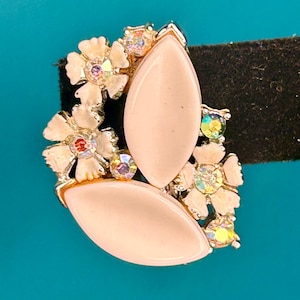 May include: A pair of pink and white flower-shaped earrings with clear rhinestones. The earrings are made of metal and have a delicate design.