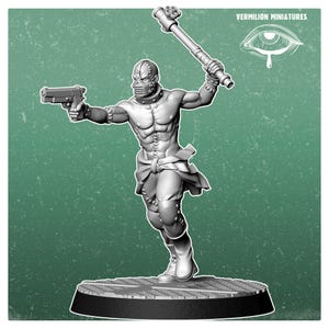 May include: A grey resin miniature figure of a muscular warrior wearing a riveted mask and collar, holding a pistol in one hand and a spiked mace in the other. The figure stands on a textured circular base, with the text Vermilion Miniatures visible.