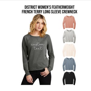May include: A dark gray long-sleeve crewneck sweatshirt with the text "custom text" in white script. The image also shows five other long-sleeve crewneck sweatshirts in different colors: coral, gray, cream, blue, and black.