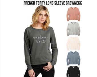 May include: A dark gray long-sleeve crewneck sweatshirt with the text "custom text" in white script. The image also shows five other long-sleeve crewneck sweatshirts in different colors: coral, gray, cream, blue, and black.
