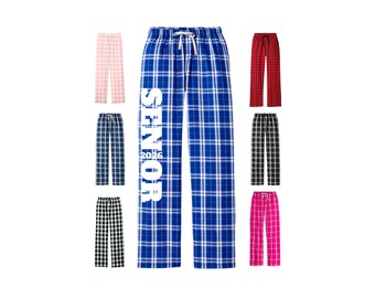 May include: Assortment of plaid pajama pants in various colors, including pink, navy, black, red, and hot pink. One pair is blue with the word "SENIOR" and the year "2026" printed vertically. All pants have a drawstring waist.