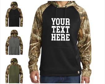 May include: Black hoodie with camouflage sleeves and hood, featuring the text "YOUR TEXT HERE" in white block letters. Three additional hoodies in black, gray, and olive green are shown on the left.