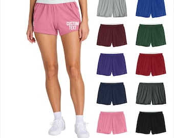 May include: A woman wearing pink athletic shorts with a white waistband and the text "CUSTOM TEXT". The image also shows examples of athletic shorts in various colors, including gray, blue, green, and black.