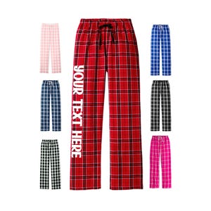 May include: Red and white plaid pajama pants with the text "YOUR TEXT HERE" printed on the left leg. The pants are shown with a variety of other plaid patterns in different colors.
