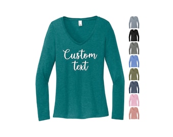 May include: Teal long-sleeve V-neck shirt with the words "Custom text" in white script. A selection of other shirt colors are displayed to the right, including gray, black, and pink.
