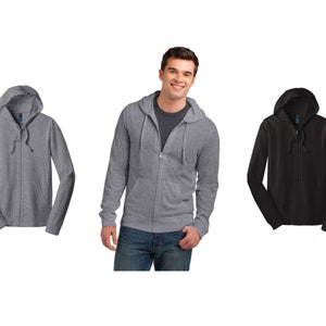 May include: Three hooded sweatshirts, one in heather gray, one in black, and one being worn by a person. The sweatshirts have a zipper closure and a drawstring hood.