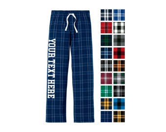 May include: Blue plaid pajama pants with a white drawstring waist and the text YOUR TEXT HERE printed vertically in white on the left leg. A color chart displays twenty additional plaid fabric patterns in various colors and combinations.