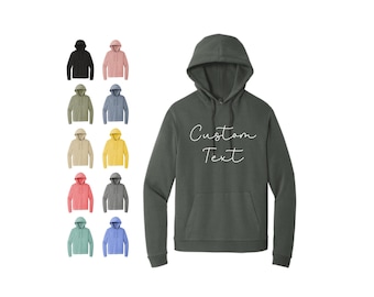 May include: A dark gray hooded sweatshirt with the text "Custom Text" in white script on the front. The sweatshirt is shown in a variety of colors, including black, pink, light blue, green, yellow, coral, gray, and light blue.