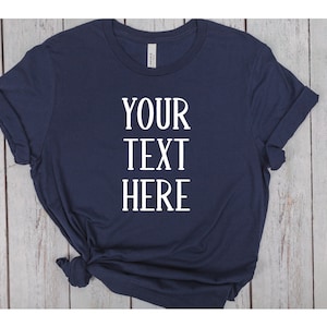 May include: A navy blue t-shirt with the text "YOUR TEXT HERE" printed in white on the front.