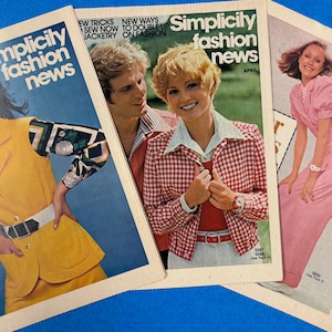 May include: Three vintage Simplicity Fashion News magazines featuring models in various outfits. The covers display text including Simplicity fashion news, 20 ways to make it say today, and April. The magazines show yellow, red, and pink clothing.